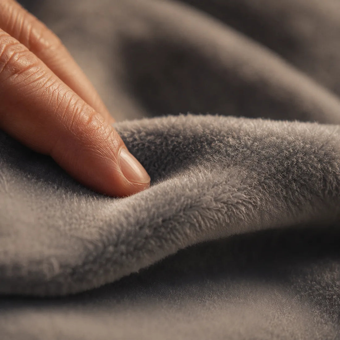 Macro close-up of a fingertip gently touching the soft brushed fleece fabric texture